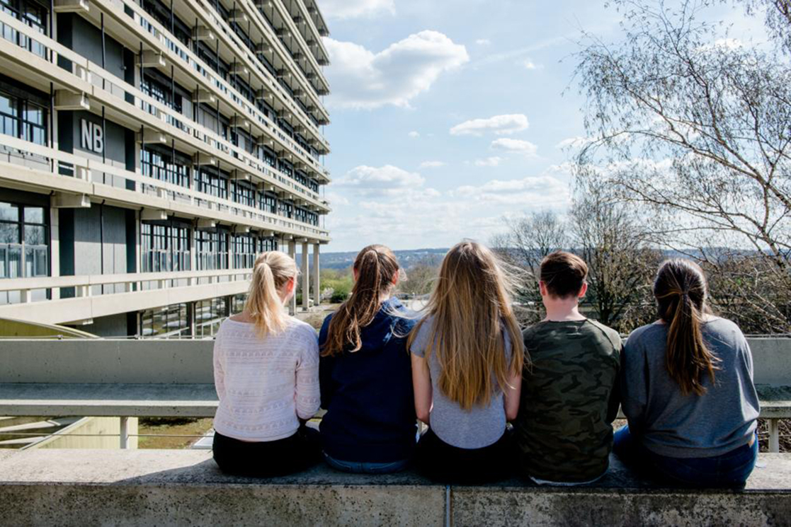 Five students sitting on a balustrade on the RUB campus