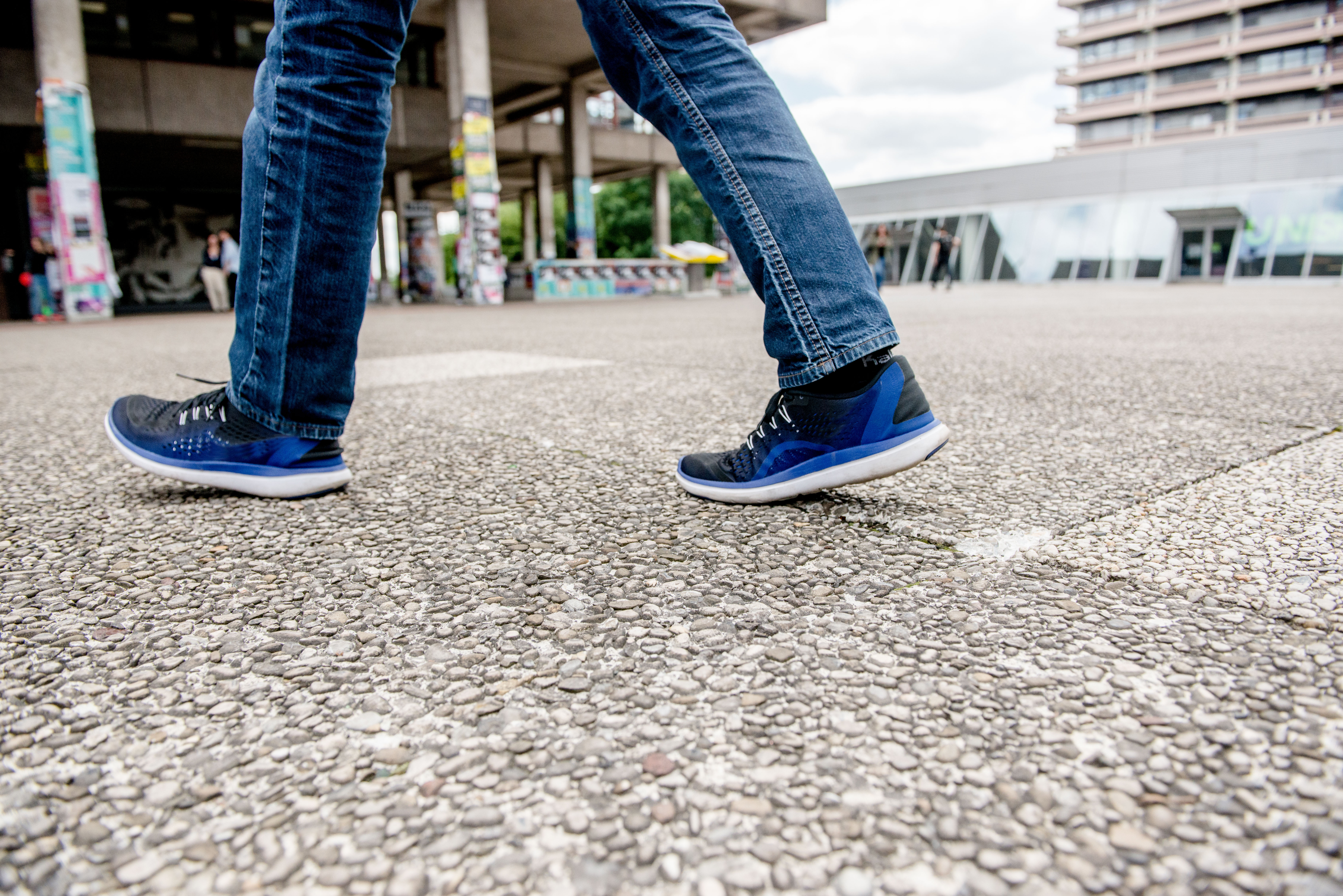 Das Bild zeigt die Beine einer Person, die über die so genannten "Klapperplatten" auf dem RUB-Campus läuft.