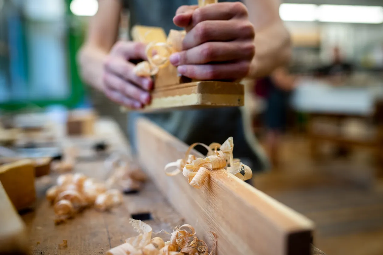 Ein Mann hobelt Holz.