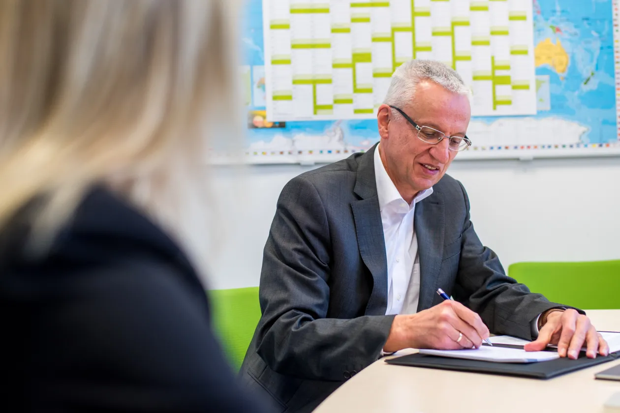 Mann schreibt in ein Dokument.