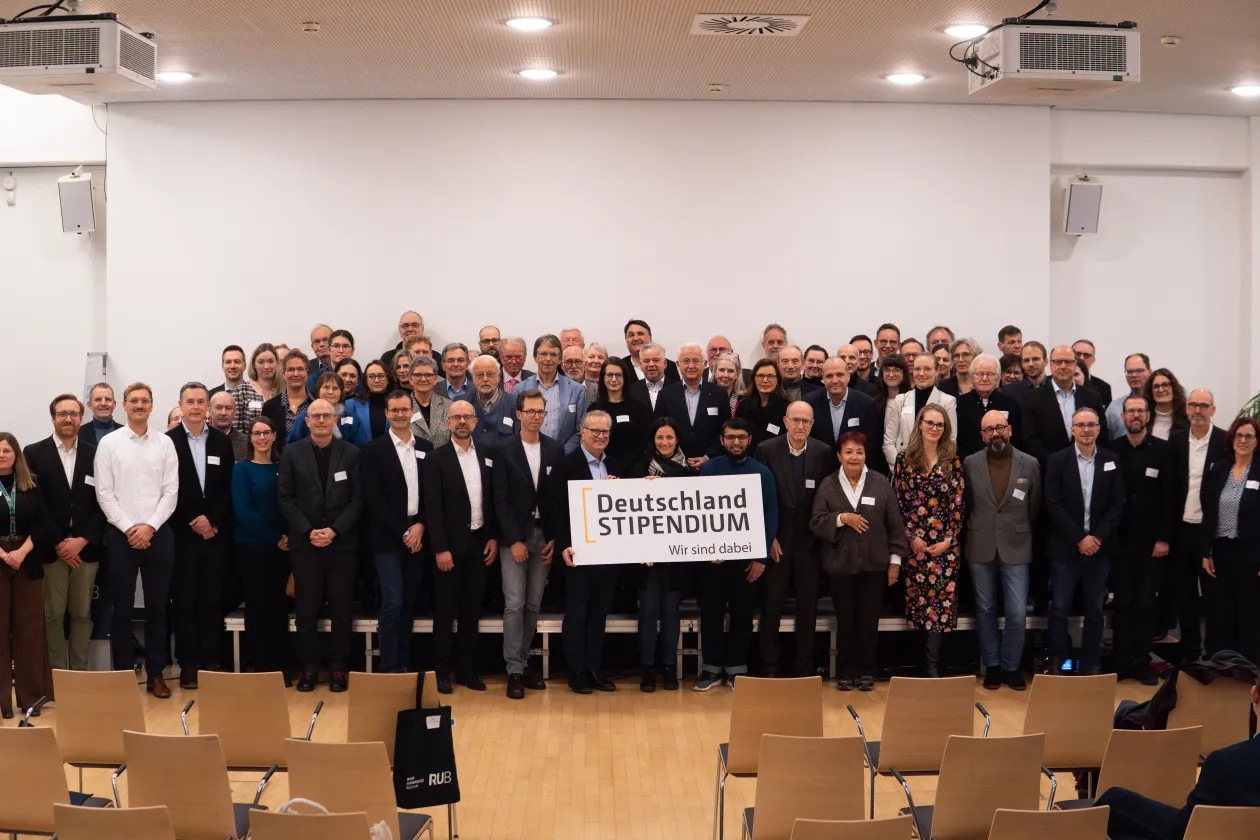 Foto: Gruppenfoto der Teilnehmer*innen der Stipendienfeier 2026. In der Mitte halten die Personen das Logo des Deutschlandstipendiums.