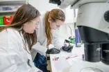Two female reserchers analyse a sample