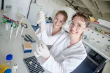 Two young female researchers in white coats in the laboratory