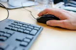 Hand klickt auf einer Computermaus.