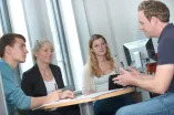 Vier Mitarbeitende sitzen an einem Tisch und unterhalten sich.