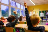 Grundschulkinder melden sich in der Klasse