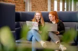 Zwei Studentinnen sitzen auf dem Sofa.