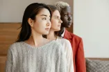 Drei Frauen verschiedener Ethnien schauen mit ernstem Gesichtsausdruck nach rechts.