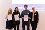 Foto: Vier Personen stehen nebeneinander und gucken in die Kamera. Drei Personen links halten alle jeweils eine Urkunde in den Händen.