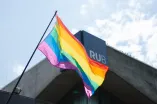 Eine Regenbogenflagge weht vor dem RUB-Schriftzug am Musischen Zentrum