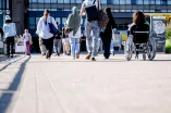 Unterschiedliche Menschen überqueren die Unibrücke, darunter eine Rollstuhlfahrerin und Personen mit Kopftuch