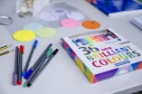 Bunte Stifte liegen auf einem Tisch. Auf der Packung steht „36 brilliant colours“ 