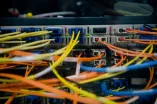 Das Bild zeigt viele bunte Kabel, die in Anschlüsse laufen