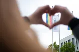 Herzförmige Hände um eine Flagge