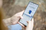 Das Foto zeigt ein Handy, das von einer Person gehalten wird, die auf der Oberfläche der Plattform KI:Connect etwas eintippt