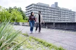 Two people are walking across the campus of Ruhr University Bochum. A large building can be seen in the background.