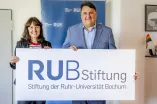 Geschäftsführerin der Stiftung der Ruhr-Universität Bochum Susanne Seiler und Rektor der Ruhr-Universität Bochum Prof. Dr. Martin Paul halten zusammen das Logo der Stiftung der Ruhr-Universität Bochum.
