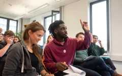  Student hebt die Hand bei einer Veranstaltung 