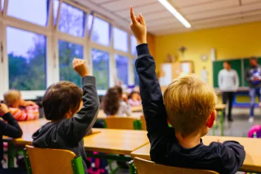 Grundschulkinder melden sich in der Klasse