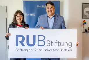 Geschäftsführerin der Stiftung der Ruhr-Universität Bochum Susanne Seiler und Rektor der Ruhr-Universität Bochum Prof. Dr. Martin Paul halten zusammen das Logo der Stiftung der Ruhr-Universität Bochum.
