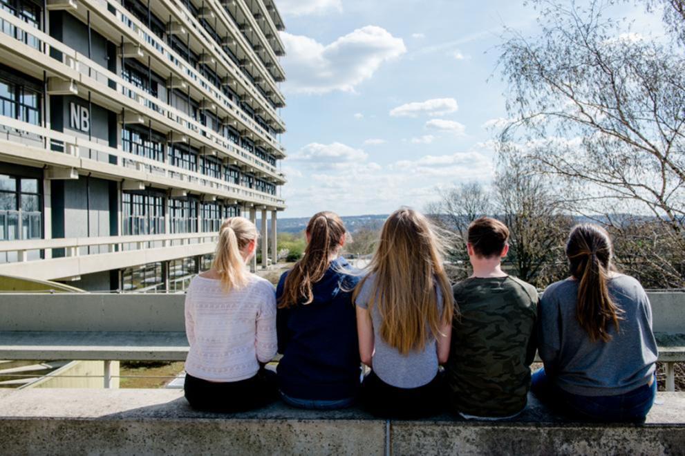 Five students sitting on a balustrade on the RUB campus