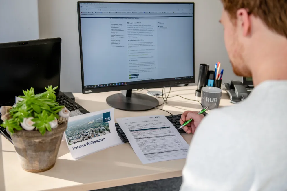 Mitarbeiter sitzt im Büro an seinem Schreibtisch und schaut auf seinen PC-Monitor.
