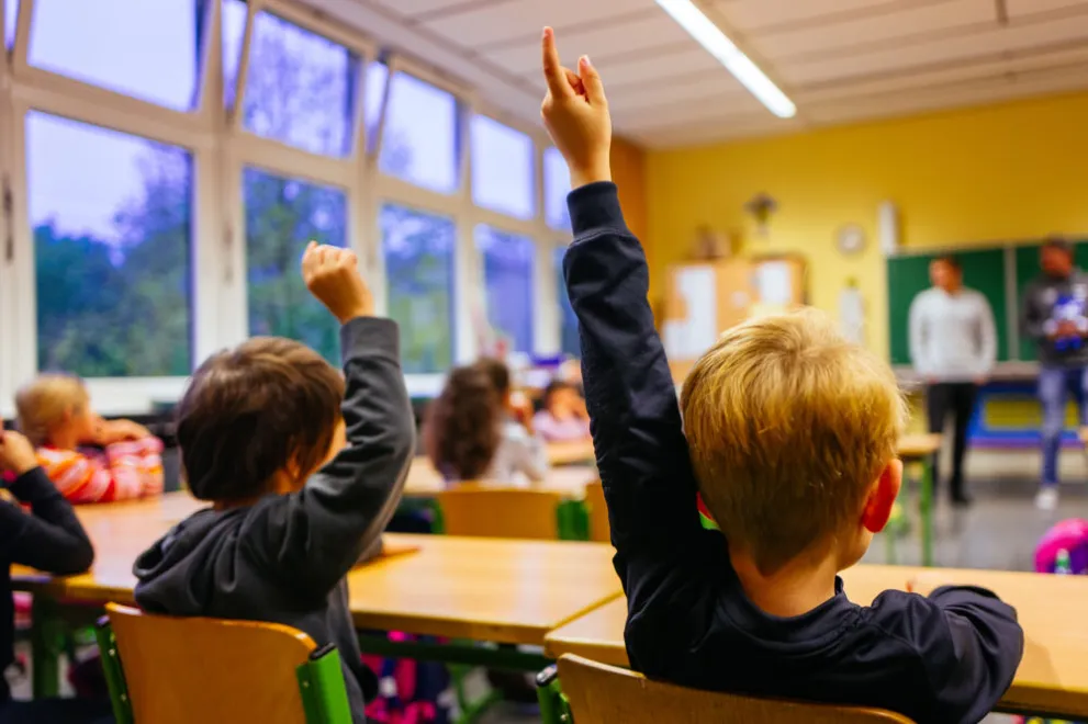 Grundschulkinder melden sich in der Klasse