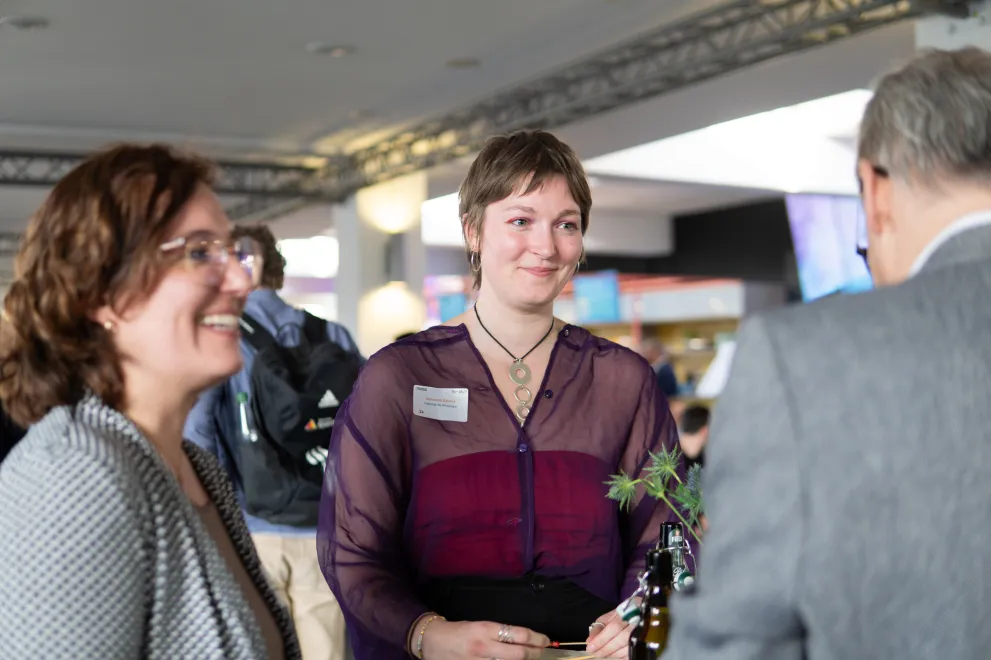 Foto: Mehrere Personen stehen lächelnd zusammen und unterhalten sich.