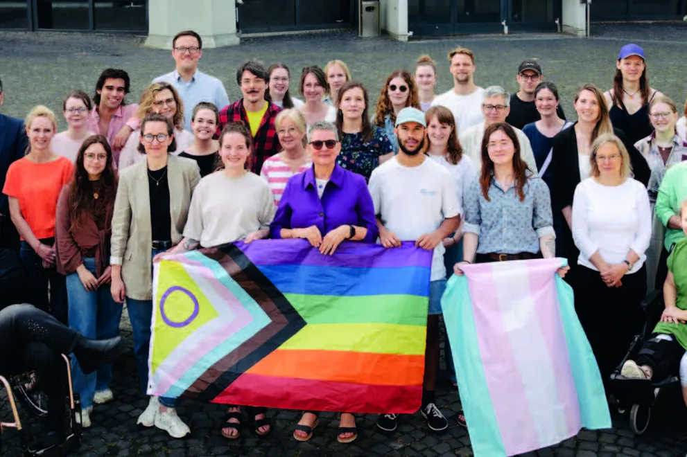 Eine große Menschengruppe steht vor dem Audimax. Einige halten Regenbogenfahnen in den Händen. Im Vordergrund ist Frau Karle, Prorektorin für Diversität, Inklusion und Talententwicklung zu sehen.