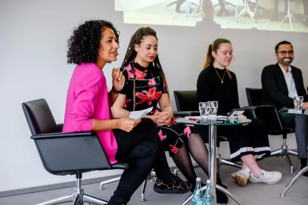 Vier Personen sitzen auf einer Bühne und sprechen miteinander. Es handelt sich um Expert*innen zum Thema Rassismus beim Diversity Sarah Vecera, Nathalie Eleyth, Bonnie Aurich, Karim Fereidooni.