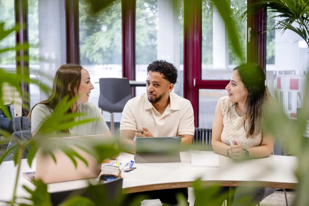 Drei Studierende mit Laptops