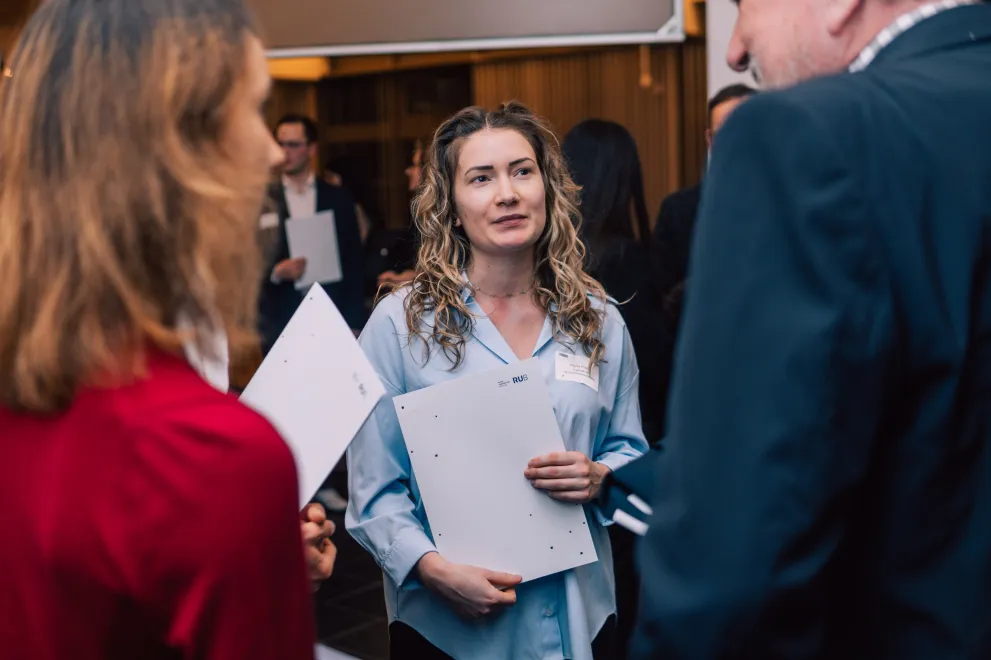 Foto: Mehrere Personen stehen im Kreis zusammen. Sie unterhalten sich.