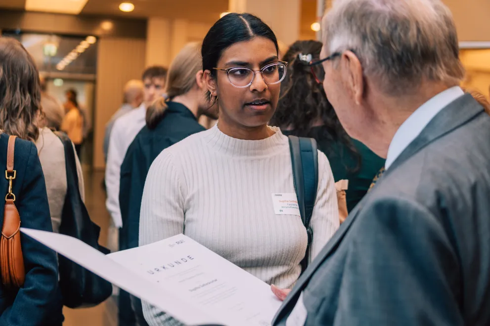 Foto: Ein Mann überreicht einer Frau eine Urkunde.