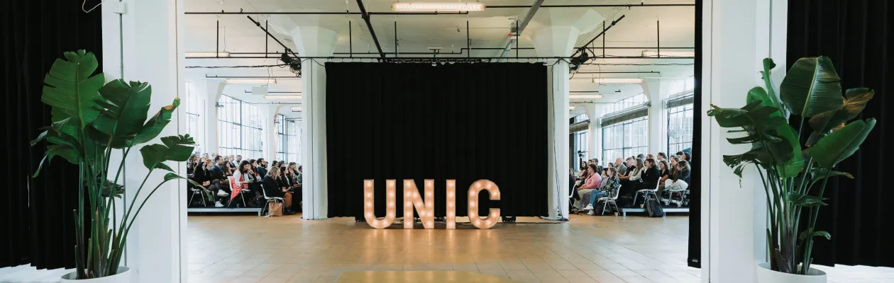 Foto: Leuchtendes UNIC Logo steht auf dem Boden bei einer Veranstaltung.