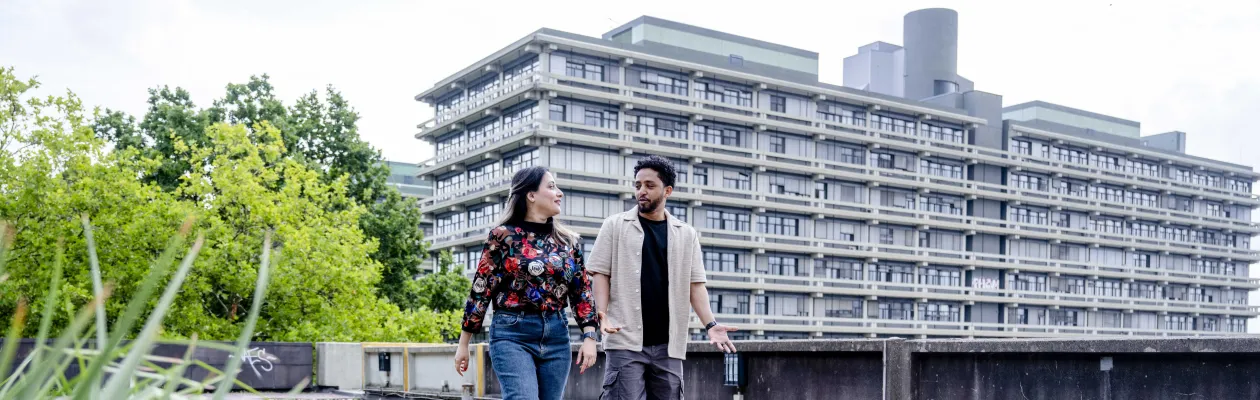 Two people are walking across the campus of Ruhr University Bochum. A large building can be seen in the background.