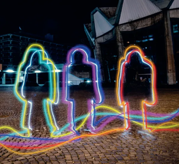 Bunte Umrisse von Personen vor einem dunklen Hintergrund
